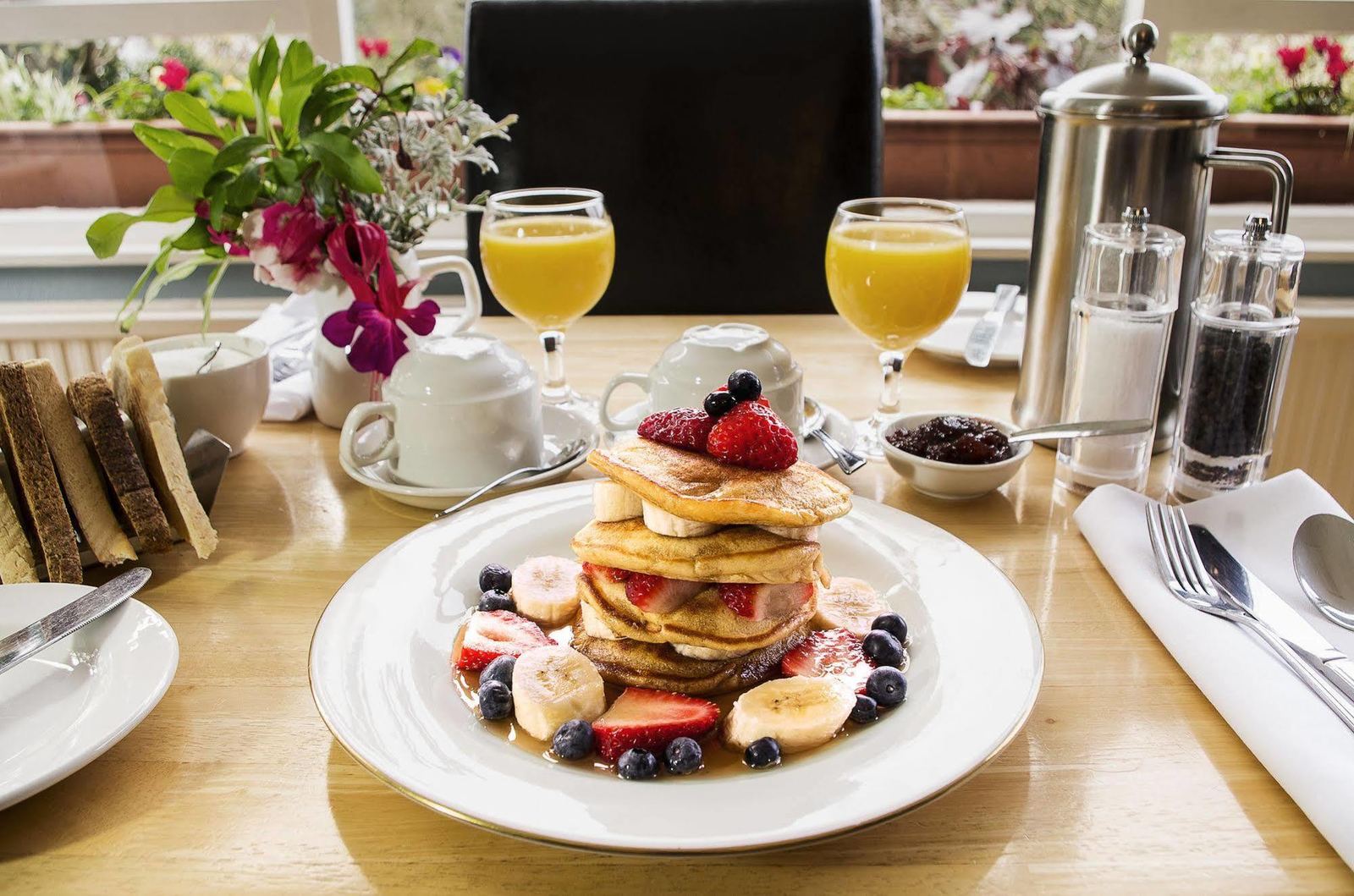 Pancakes with fruit, juice and preserves on the breakfast table